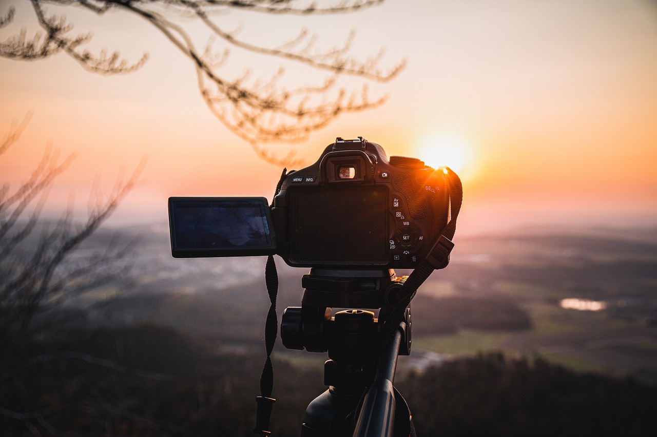 Cámara DSLR en un trípode capturando una puesta de sol en el horizonte